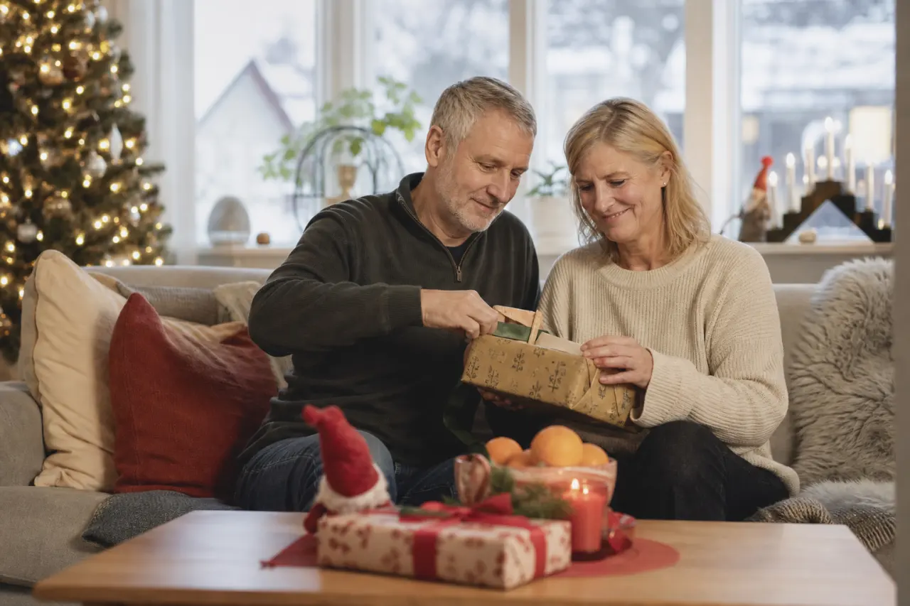 Ett äldre par öppnar en gemensam julklapp tillsammans i soffan
