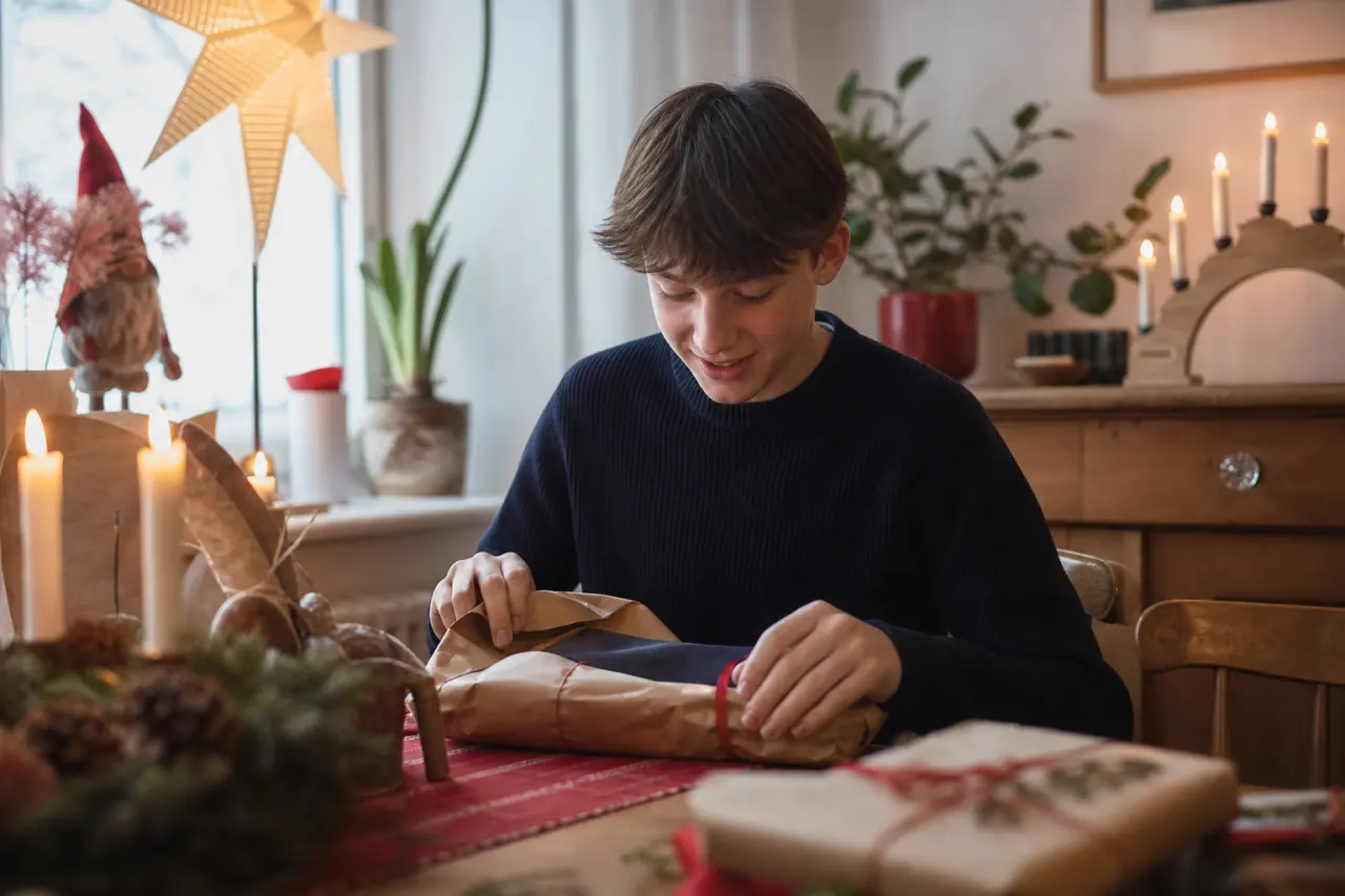 Tonåring öppnar julklapp, neutral scen utan synligt varumärke